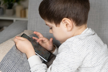 A preschool boy uses a smartphone, plays games on his phone. Screen Time, Parental Controlsの写真素材
