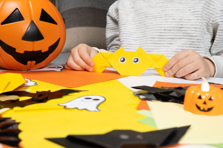 Preschool child creates Halloween origami paper bat crafts, close-up handsの写真素材