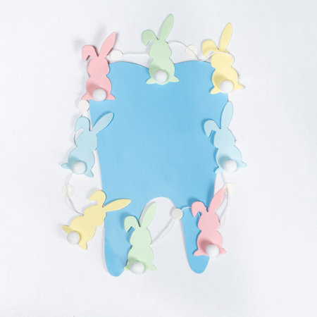 Easter dentistry. Blue tooth and garland of rabbits on a white background, top viewの写真素材