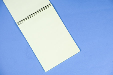 Open notepad on a blue background top view, space for text.の写真素材