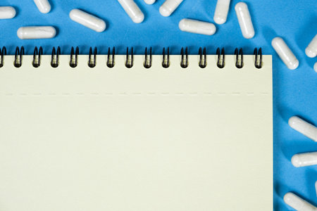 Medical notepad with pills on a blue background, space for text