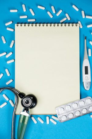 Medical mockup - notepad with stethoscope, pills and thermometer, top view, space for textの写真素材