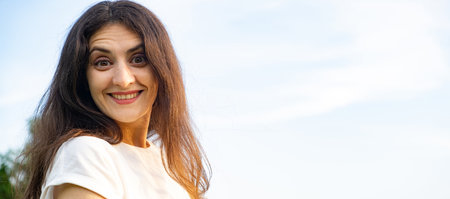 Portrait of an enthusiastic cheerful 35-year-old brunette woman against the sky, a place for textの写真素材