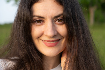 Portrait of a 35-year-old brunette woman looking at the camera smiling in nature