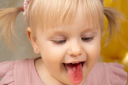 Little girl with red tongue from dye after eating cakeの写真素材