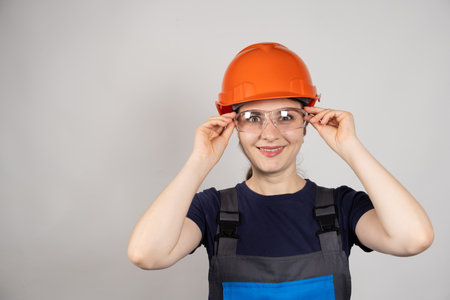 A woman in a protective helmet, glasses and overalls on a white background with space for textの写真素材