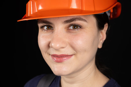 A female construction worker or engineer wearing a protective orange mask on a black background.の写真素材