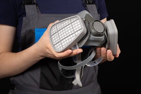 Respirator with dust and gas filters in the hands of a person on a black backgroundの写真素材