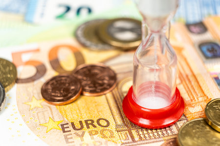 Time is money. Hourglass on euro banknotes close-up.