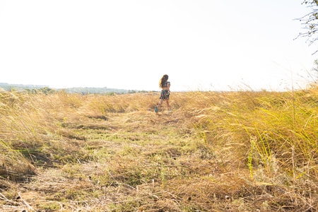 Happy little child running in a summer field of feather grass. Children's Day, happy childhood.