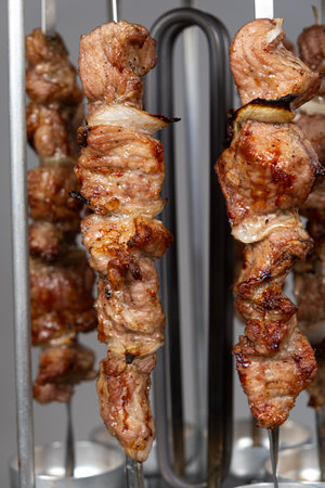 Cooking pork meat in an electric kebab maker on vertical skewers.の写真素材