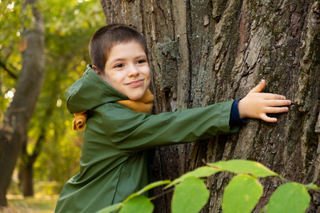 Little boy hugging a tree in the forest in autumn. A child's love for nature