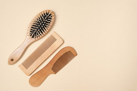 Wooden combs and hair care brush on beige background, top view, space for text.