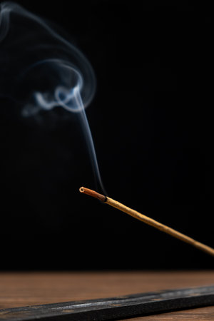 Smoke from a burning aroma stick on a black background. Incense sticks, aromatherapy and meditation.の写真素材