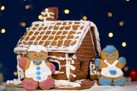 Christmas gingerbread in the shape of men is decorated with colorful sugar icing and a cookie house