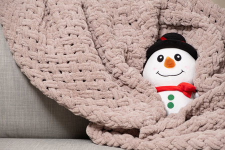 Toy stuffed snowman basking in pink plush blanket in winter