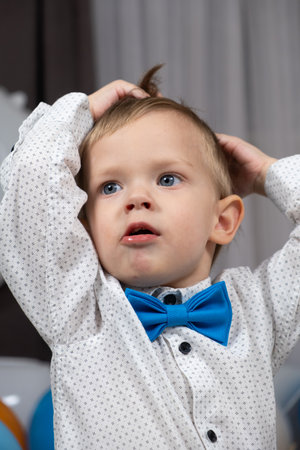 A little two-year-old boy holds his head with his handsの写真素材
