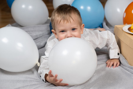 Portrait of happy toddler among white and blue balloons.の写真素材