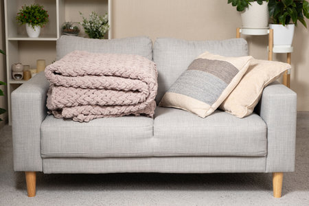 Knitted large plaid blanket in dusty rose light grayish-red color on the sofa.