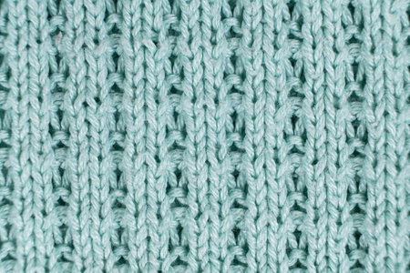 Texture and background of knitted turquoise sweater made of synthetic fabric.