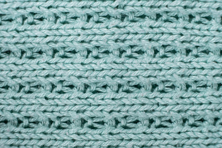 Texture and background of knitted turquoise sweater made of synthetic fabric.