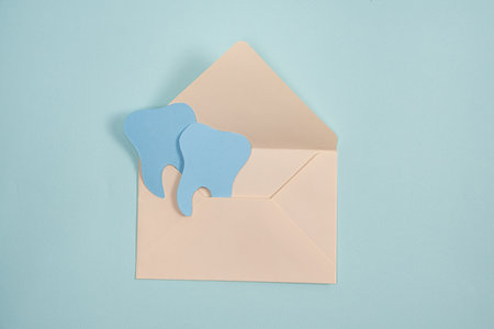 Dental greeting card. Two paper teeth in an envelope on a blue background, copy space for text.の写真素材
