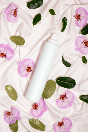 Fabric softener with floral scent among flowers on bed linen top view.の写真素材