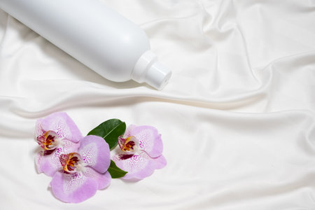 Natural fabric softener on satin fabric with orchid flowers, space for textの写真素材