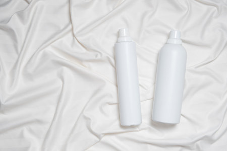 Liquid laundry detergent and fabric softener on bedding, space for textの写真素材