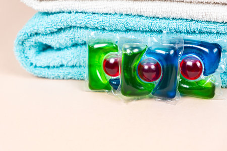 Laundry pods on beige background with soft towels, place for text.の写真素材