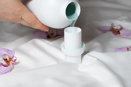 The process of pouring natural eco gel liquid laundry detergent from the bottle into the capの写真素材