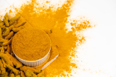 Turmeric powder, spices and dried root on white background. Top view, copy space for text.