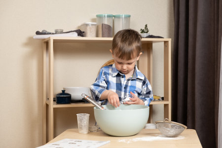 Cute toddler making cookie dough. Toddlers in the kitchen.の写真素材