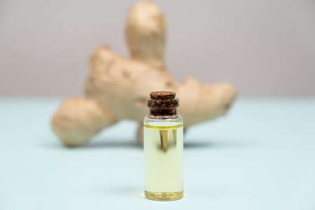 Natural Ginger Essential Oil in a Glass Bottle on a Gray Blue Background