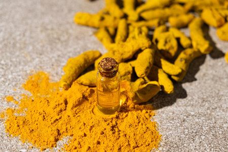 Natural Turmeric Oil in a Glass Bottle with Ground Turmeric Powder and Dry Turmeric Rootの写真素材