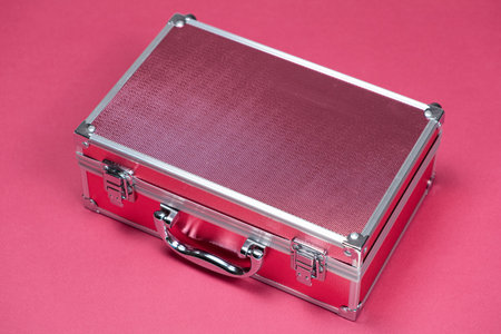 Small suitcase, box for cosmetics on a pink background