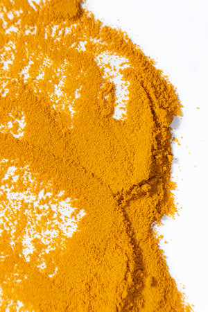 A smear of turmeric on a white background, top view.