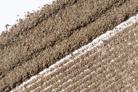 Abstract striped brown ground black pepper background top view. Creativity in cooking