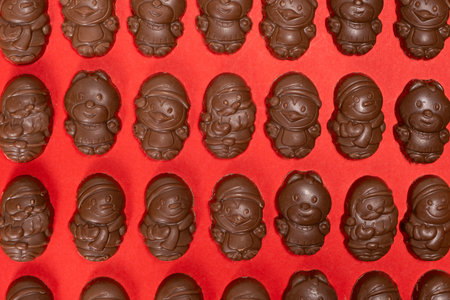 Chocolates in the shape of Christmas figures on the red background top view