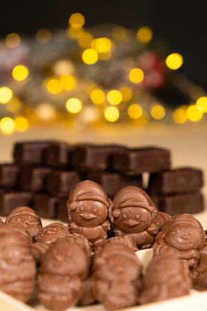 Chocolates in the shape of Christmas figures on the background of a flashing garlandの写真素材