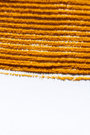 Abstract striped orange background of spilled turmeric on white background
