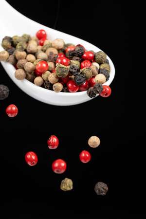 Different types of peppercorns pouring. Red, green, white and black pepper