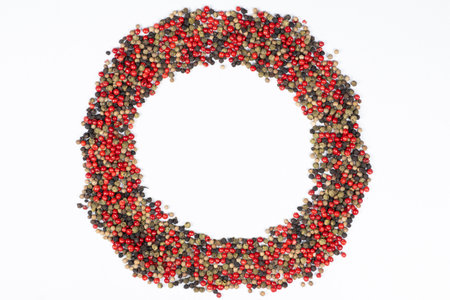 Frame of different varieties of peppercorns on a white background, top view, place for text