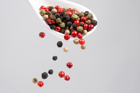 Different types of peppercorns pouring. Red, green, white and black pepper