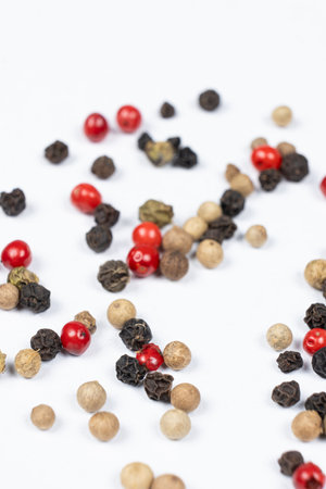 Red, green, white and black peppercorns on a white backgroundの写真素材