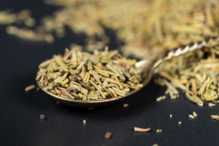 Spoon seasoning dry chopped rosemary on black backgroundの写真素材