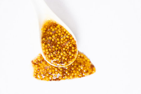 Traditional French Dijon mustard in a spoon on a white background.