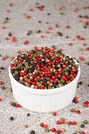 Multicolored peppercorns on a stone gray background
