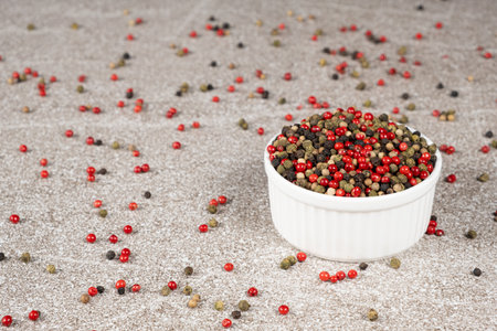 Multicolored peppercorns on a stone gray background