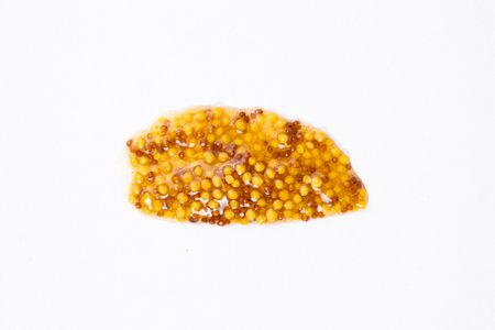 Smear of French Dijon mustard on a white background, top view.
